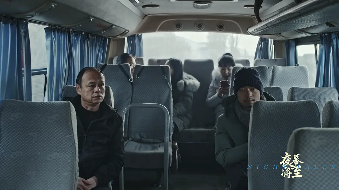 梁哲坐在回乡的中巴车后排，对面是一同回乡的同乡们
